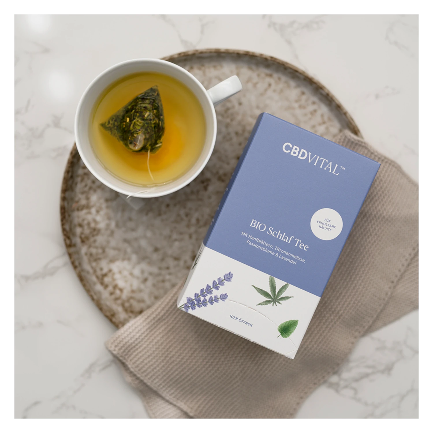 BIO Schlaf Tee von CBD VITAL mit Hanf, Lavendel & Passionsblume – Verpackung neben aufgebrühtem Tee in Tasse. Jetzt bei cbd-cannabidiol.de kaufen!